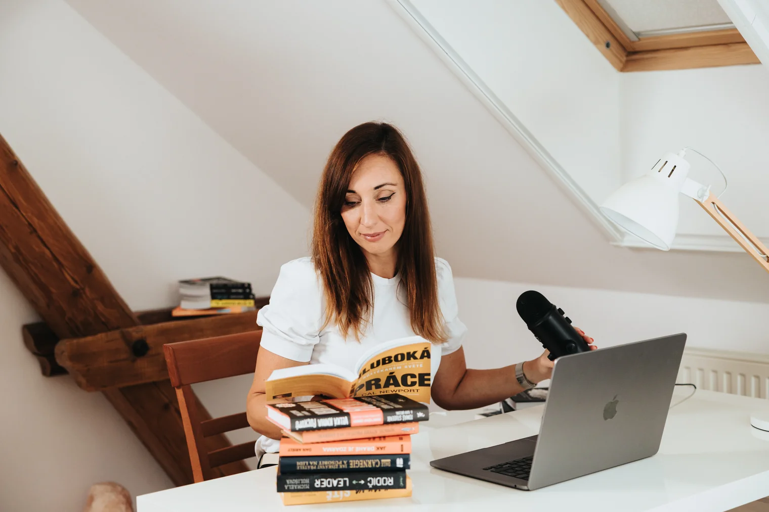 Aneta Kořínková při práci s knihami, mikrofonem a notebookem